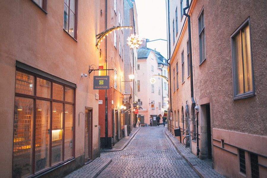 Narrow pedestrian alley between old residential buildings in Gamla Stan at twilight