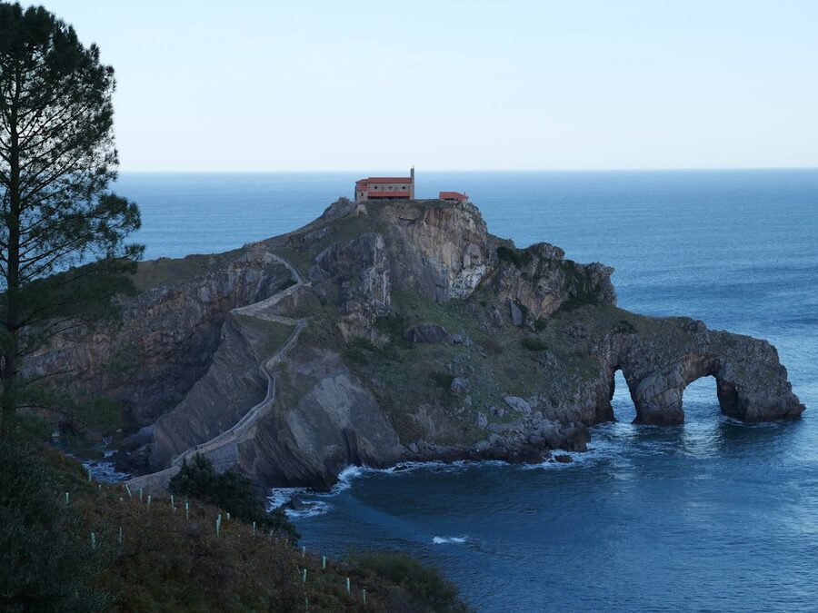 Panoramic view of the stone arch bridge and winding pathway to Gaztelugatxe island