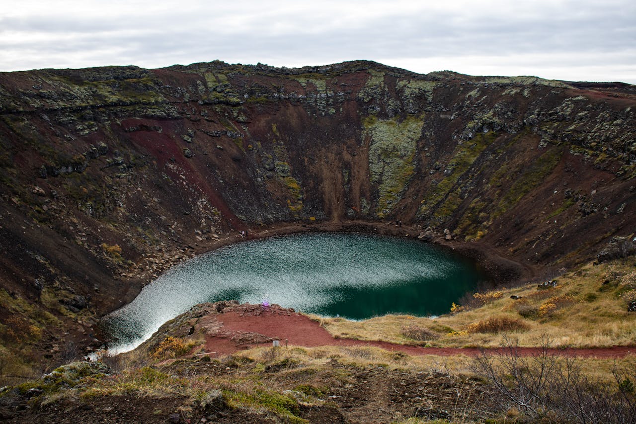 Kerid volcanic crater with green lake surrounded by red volcanic rock in Iceland