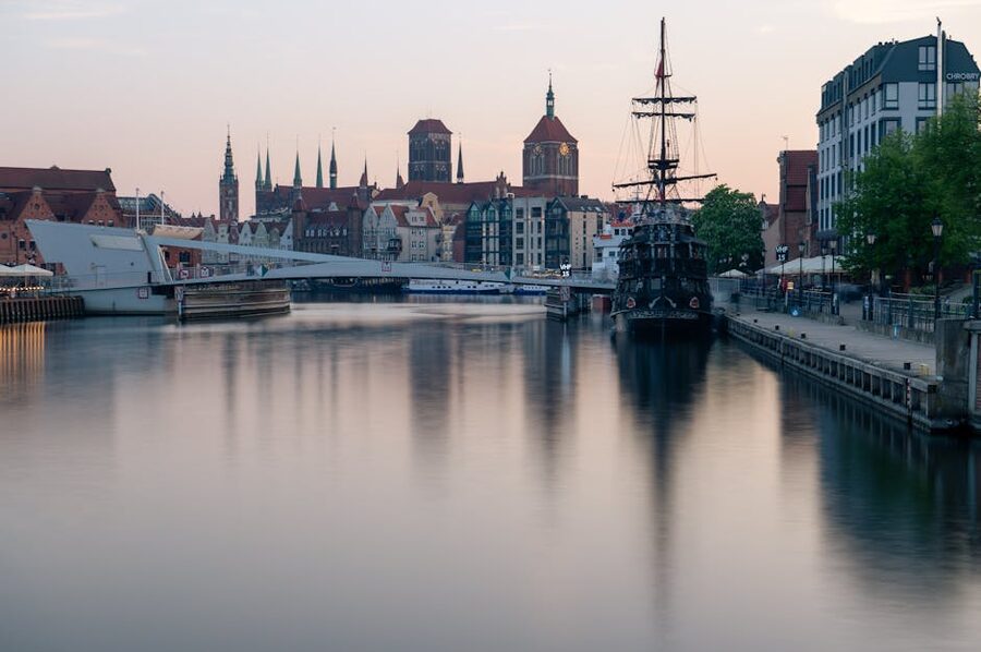 Classic ship and Gdańsk skyline under a serene sunset on the Motława River