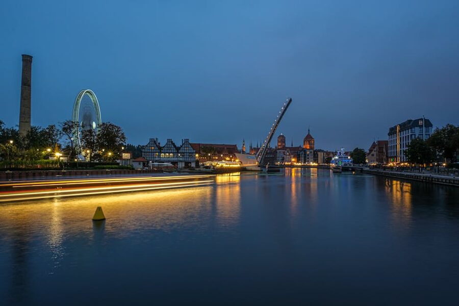 Illuminated Gdańsk waterfront seen from the Motława River at night