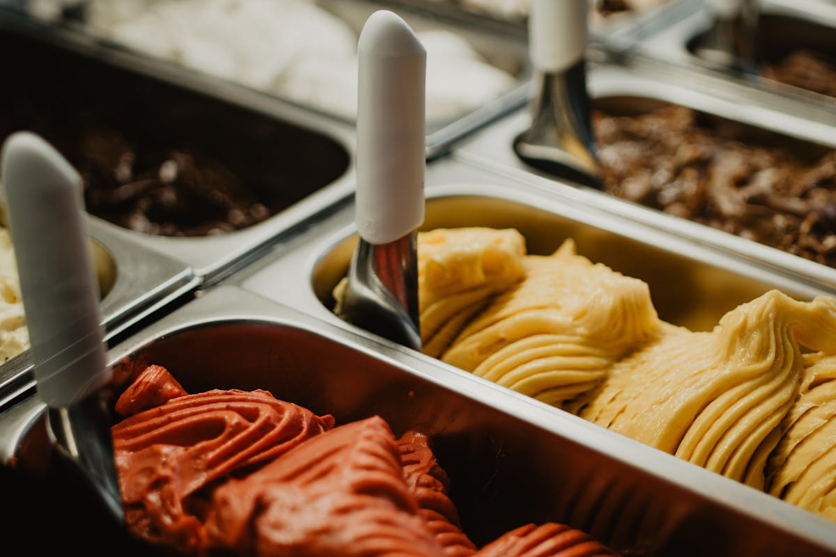 Colorful gelato flavors displayed in metal trays at a gelateria