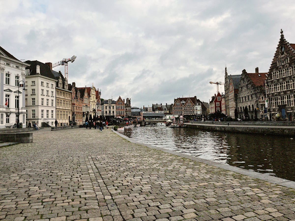 Cobblestone street with medieval buildings and canal in Ghent Belgium