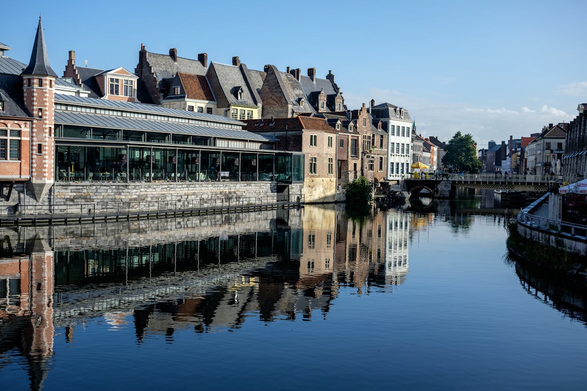 Historic buildings reflected in canal water at Graslei quay Ghent Belgium