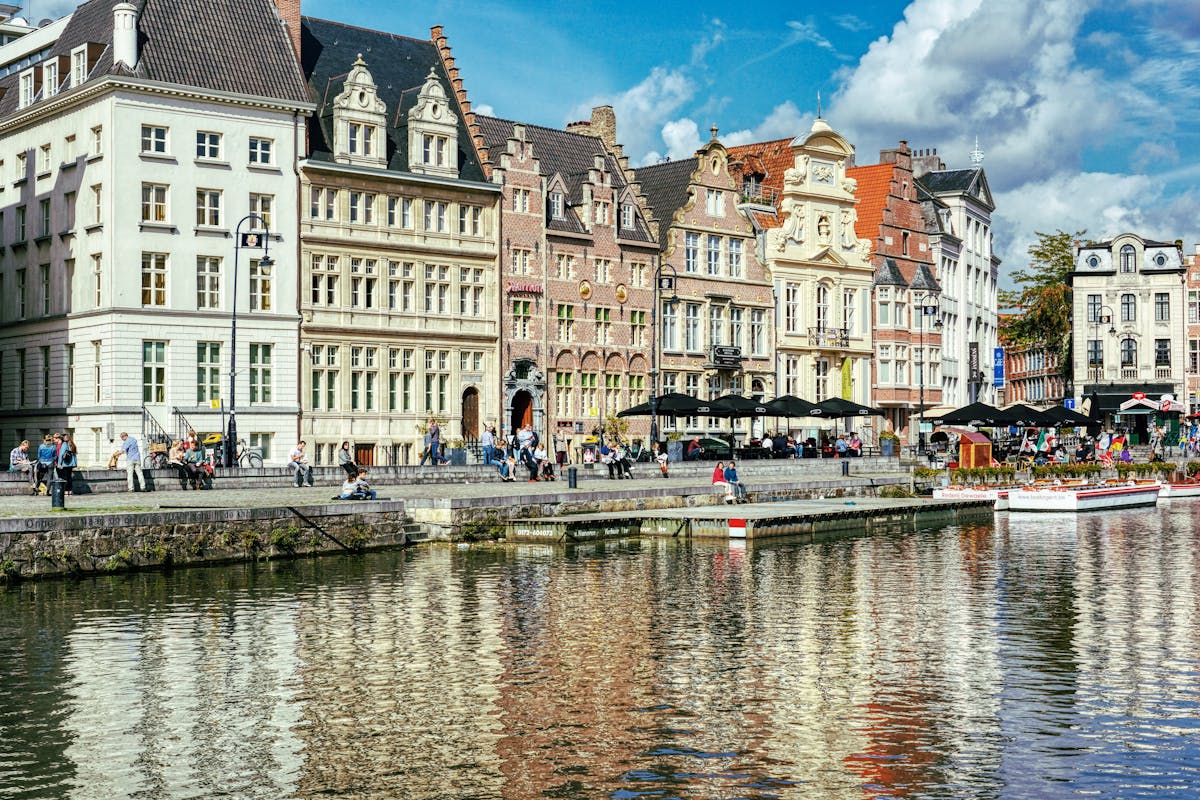 People walking along the river near historic buildings in Ghent Belgium