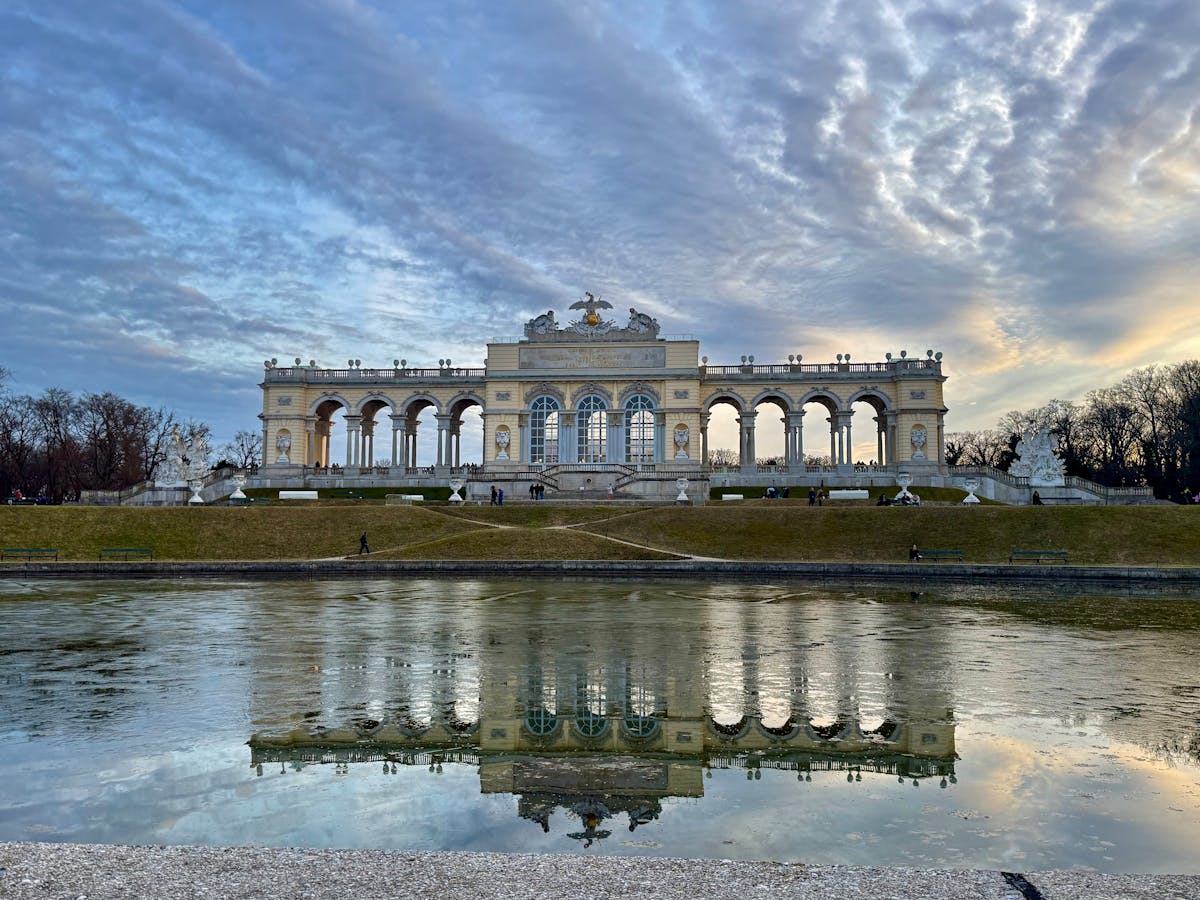 The Gloriette reflected in still water at sunrise in Schonbrunn gardens