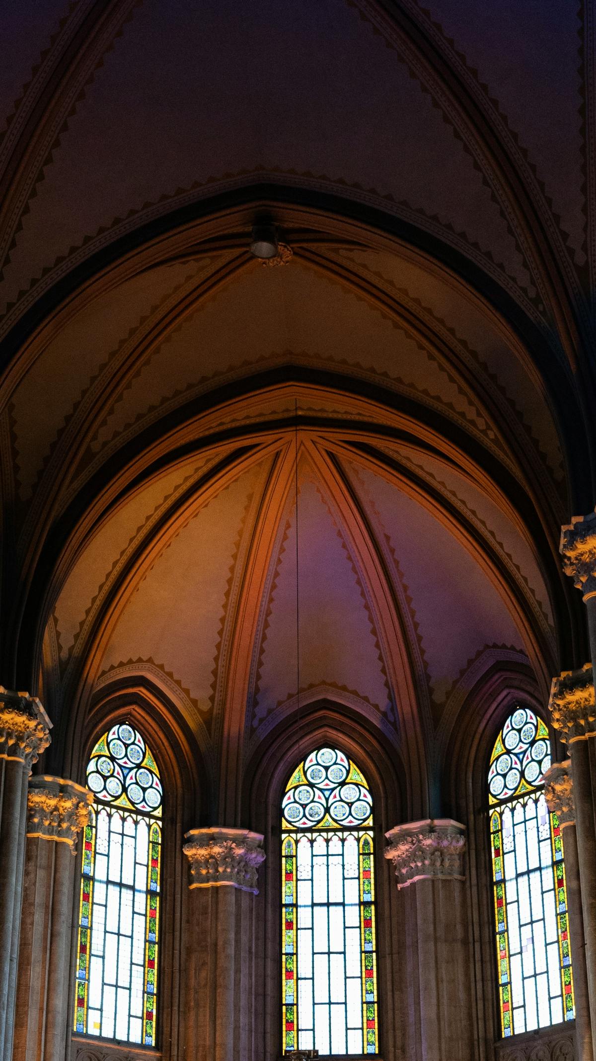 Illuminated Gothic cathedral interior with soaring vaulted ceiling and stained glass windows