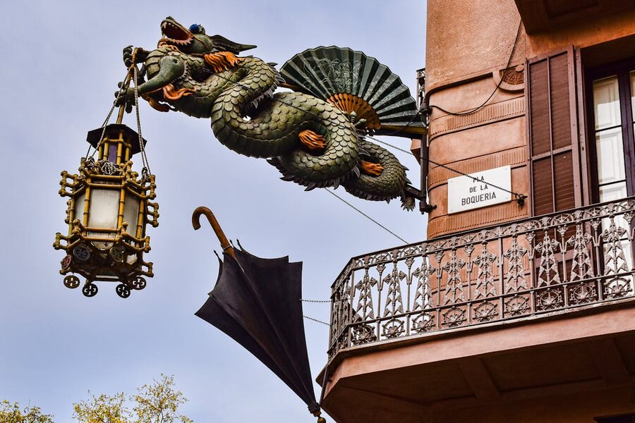 Dragon sculpture holding a lantern on a Barcelona building facade