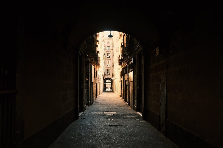 Dark stone archway leading into a narrow Barcelona alley