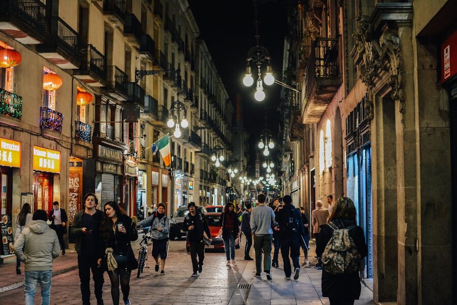 People walking through Barcelona old town at night under warm street lamps