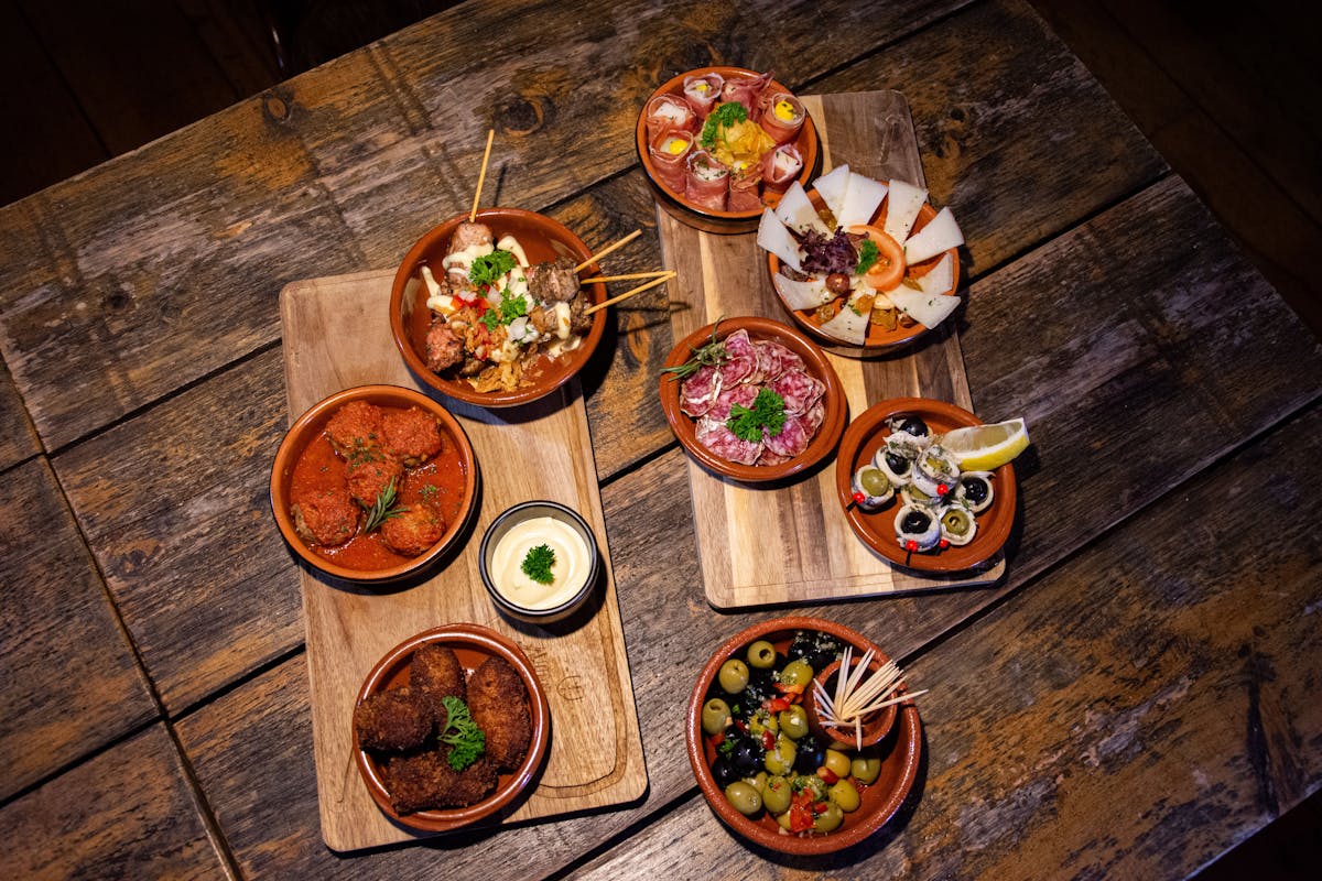 Flat lay of diverse gourmet tapas dishes on a rustic wooden table