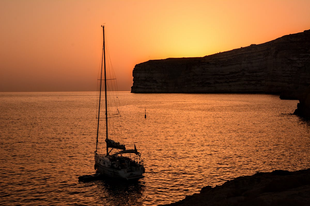 A sailboat anchored in calm waters during sunset in Malta