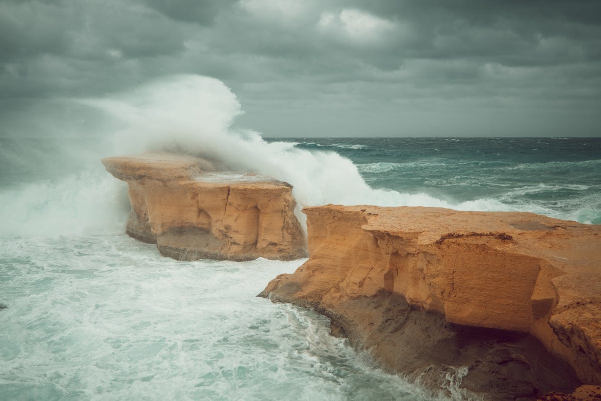Waves crashing against limestone cliffs in Gozo Malta