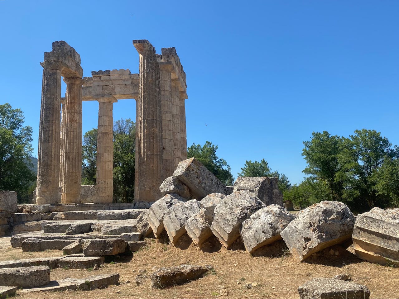 Scattered ancient Greek ruins with fallen columns and stone blocks