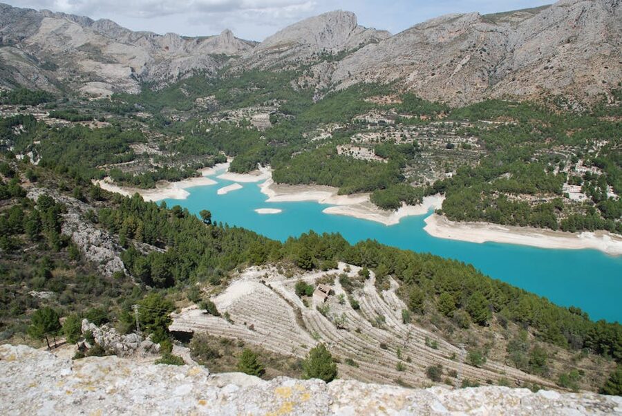 Aerial view of the turquoise Guadalest Reservoir surrounded by mountains