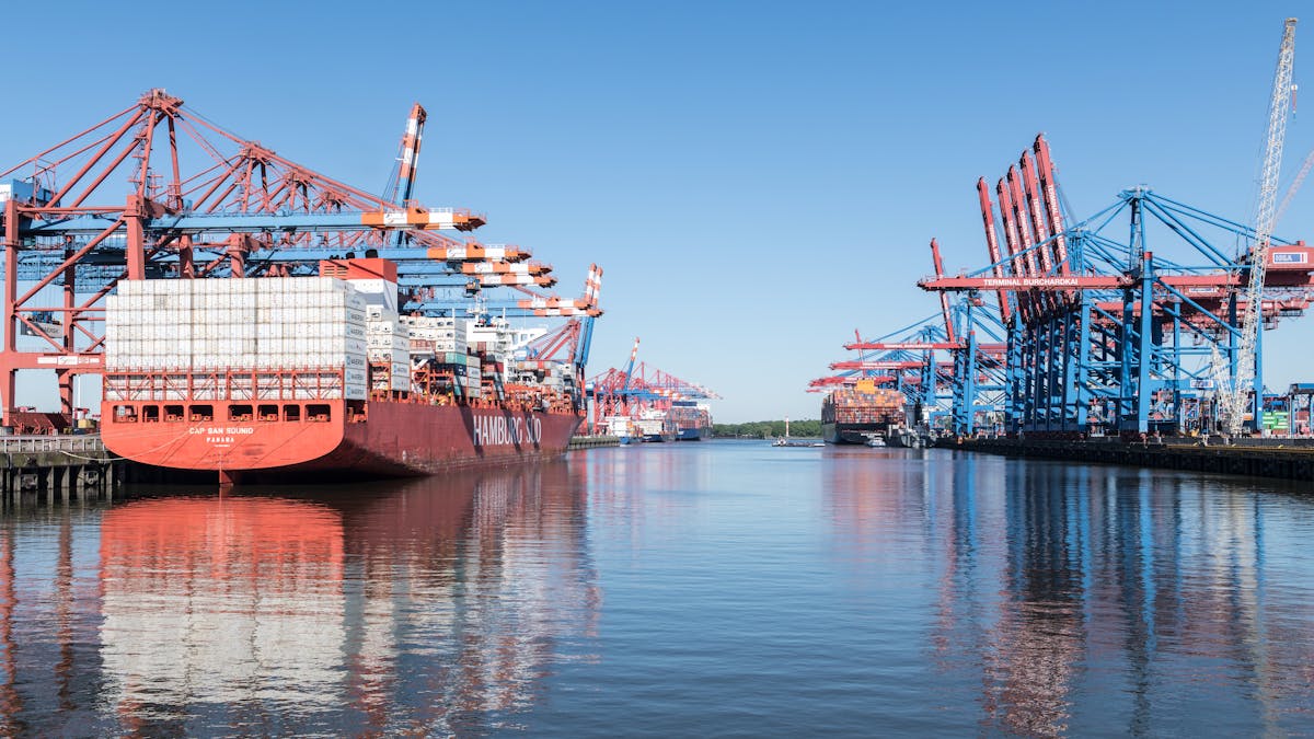 Wide view of Hamburg harbor from the water with cranes in the distance