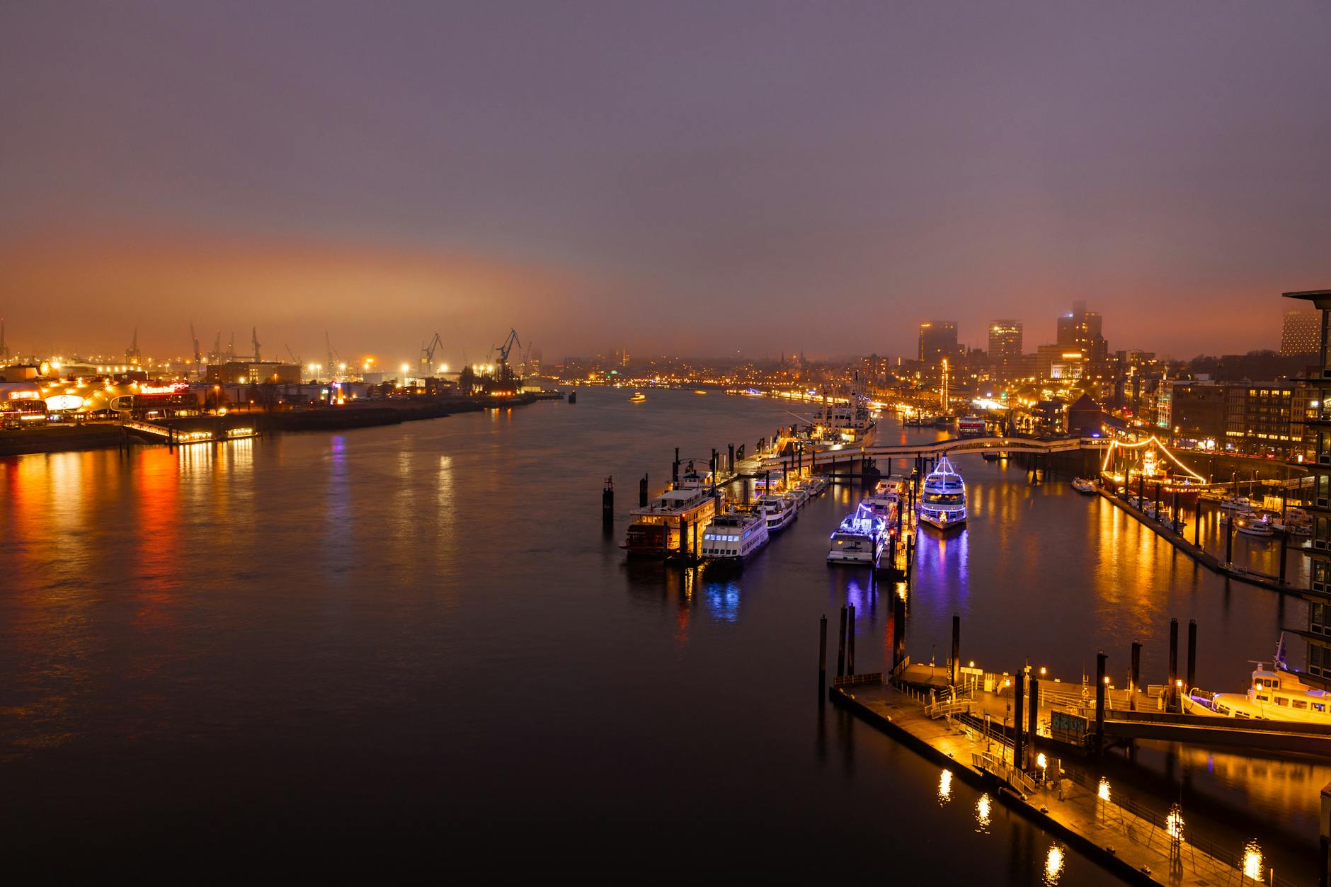 Hamburg harbor lit up at night with boats and city lights