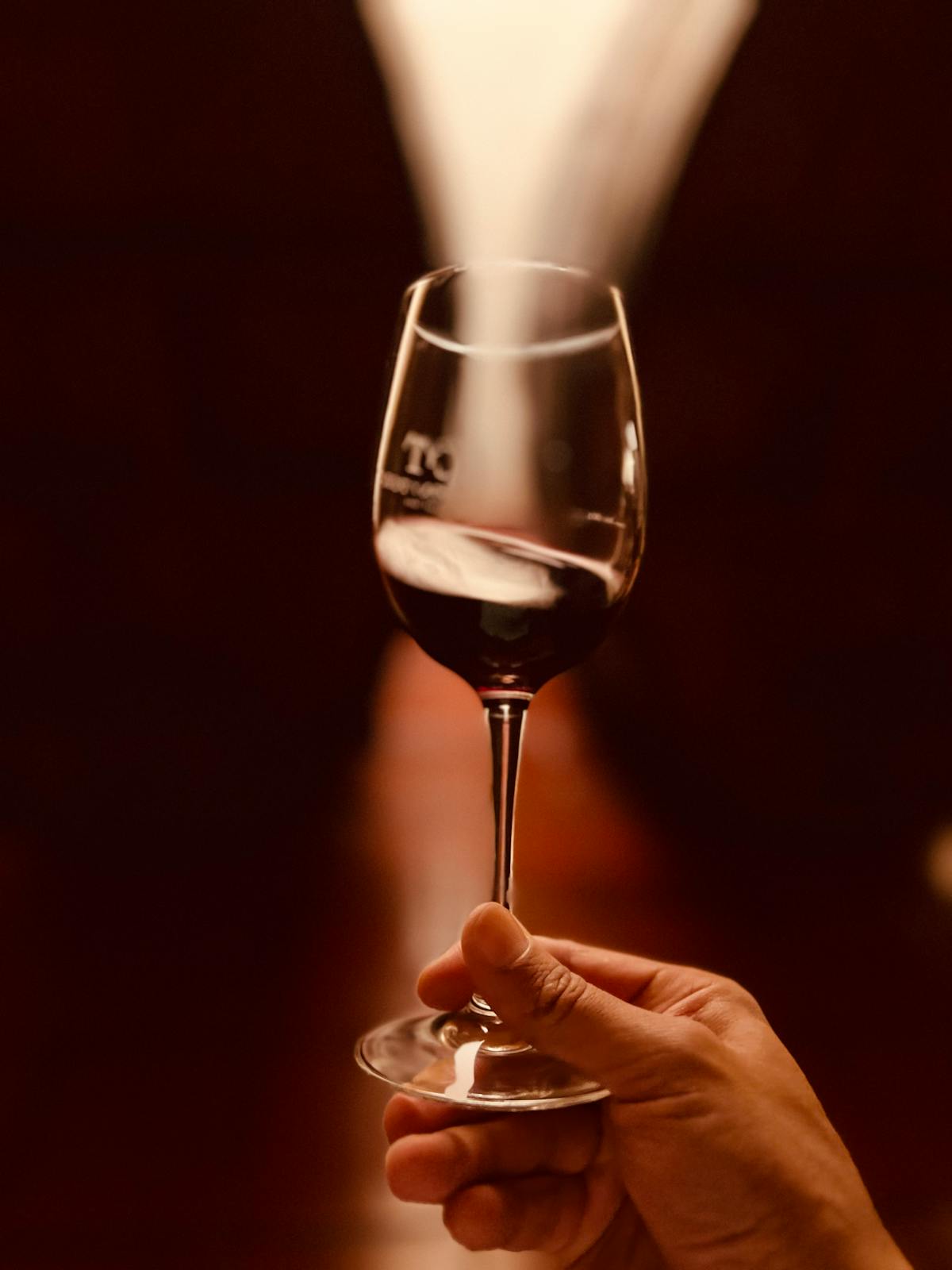 Close-up of hand holding wine glass with warm blurred background