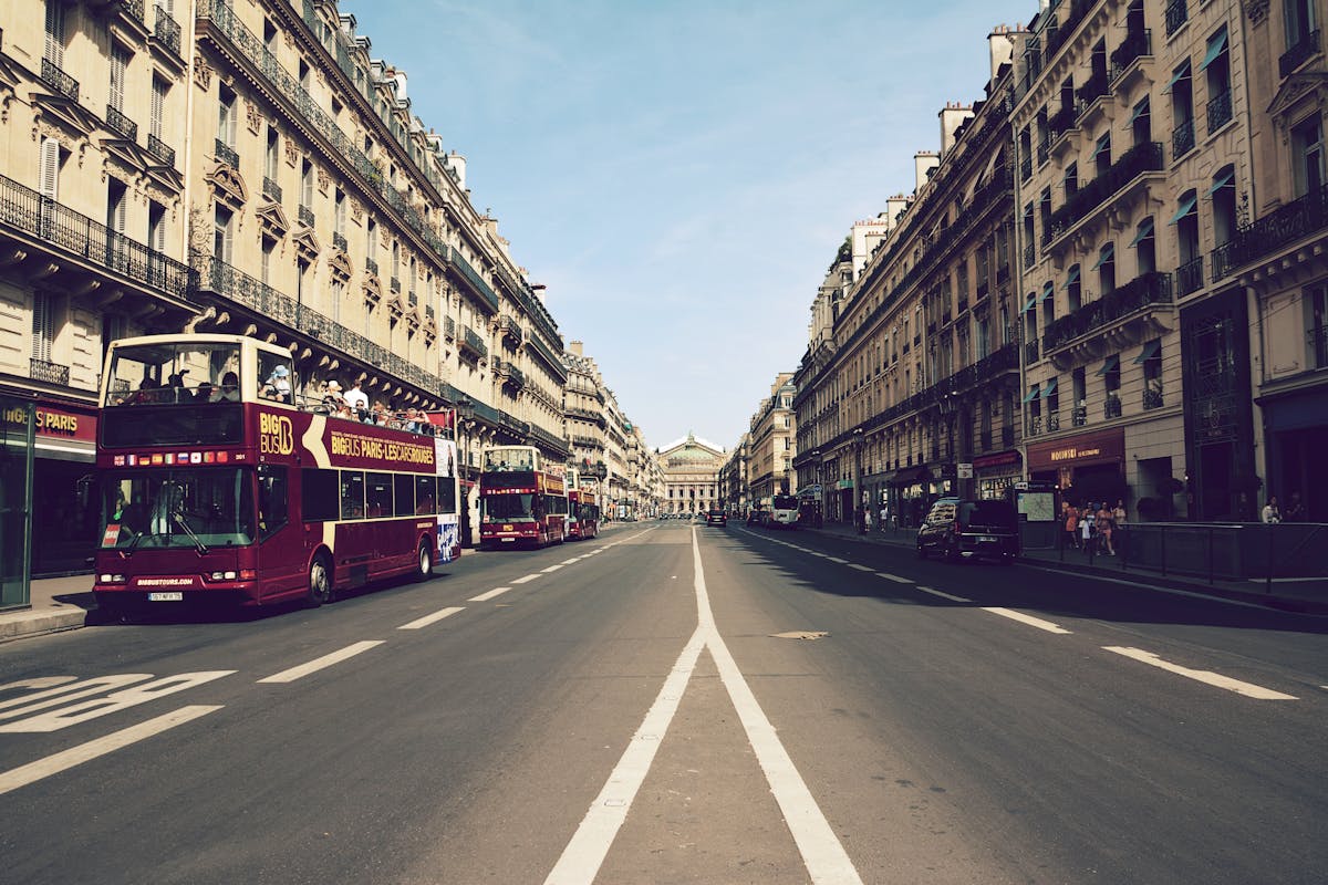 Sightseeing buses on Haussmann Boulevard in Paris with the Palais Garnier in the background