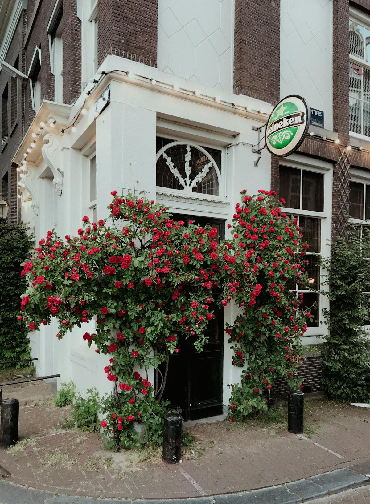 Flowers adorning a historic building entrance with Heineken signage in Amsterdam