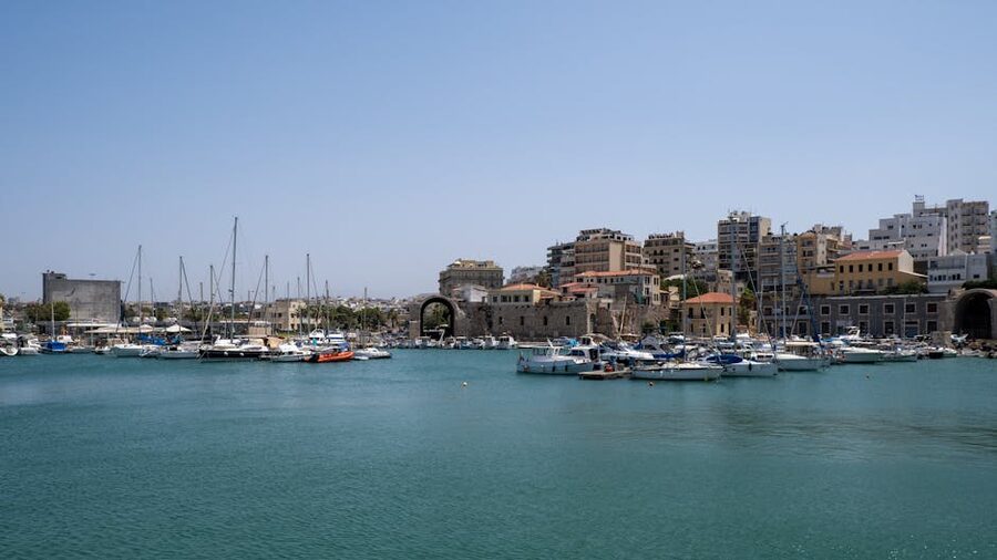 Heraklion harbor sailboats and cityscape