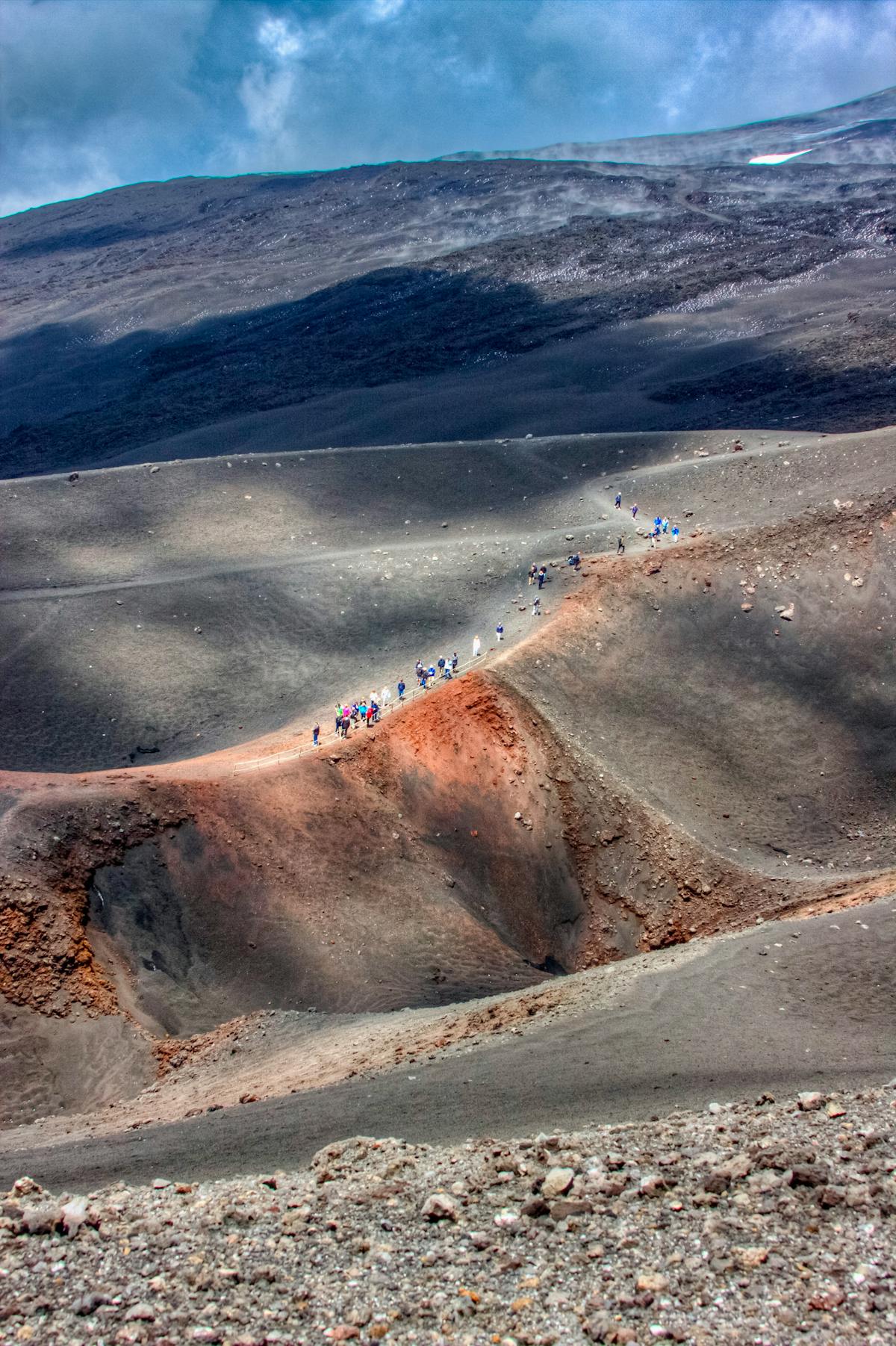 Hikers making their way across the volcanic terrain on Mount Etna