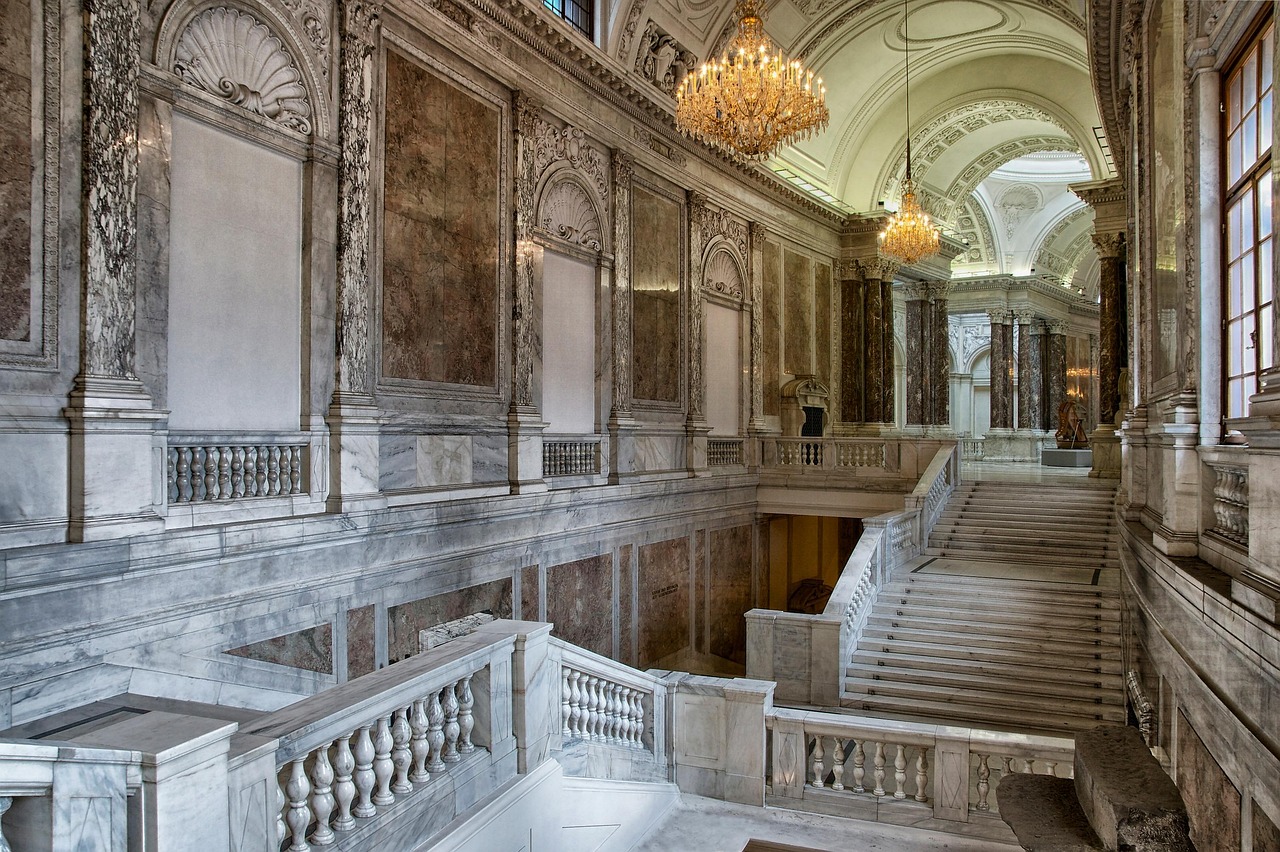 Grand marble staircase inside the Hofburg Palace with ornate chandeliers and columns
