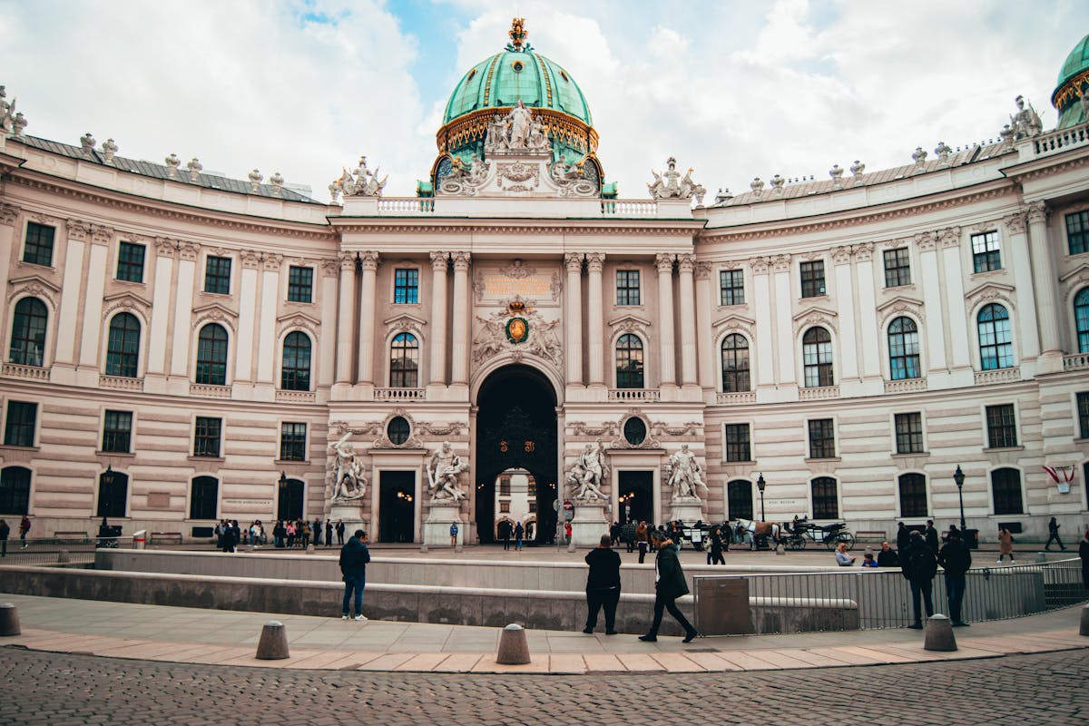 The Hofburg Palace facade with visitors walking in front on a cloudy day in Vienna