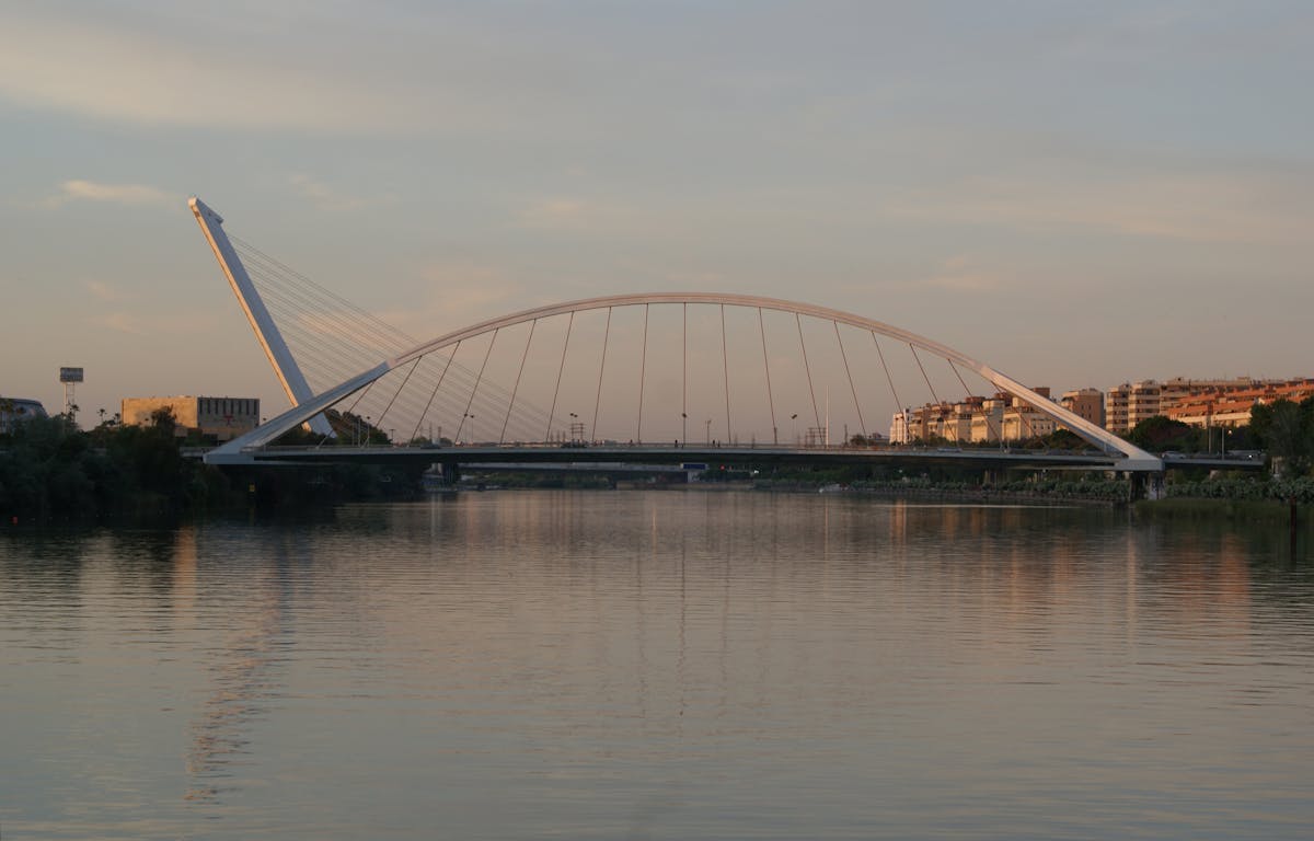 La Barqueta Bridge over the Guadalquivir River in Seville at evening with lights reflected on the water
