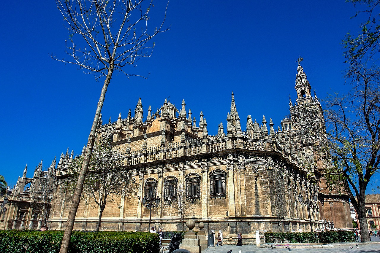 The Giralda tower and Seville Cathedral with ornate architecture against a blue sky