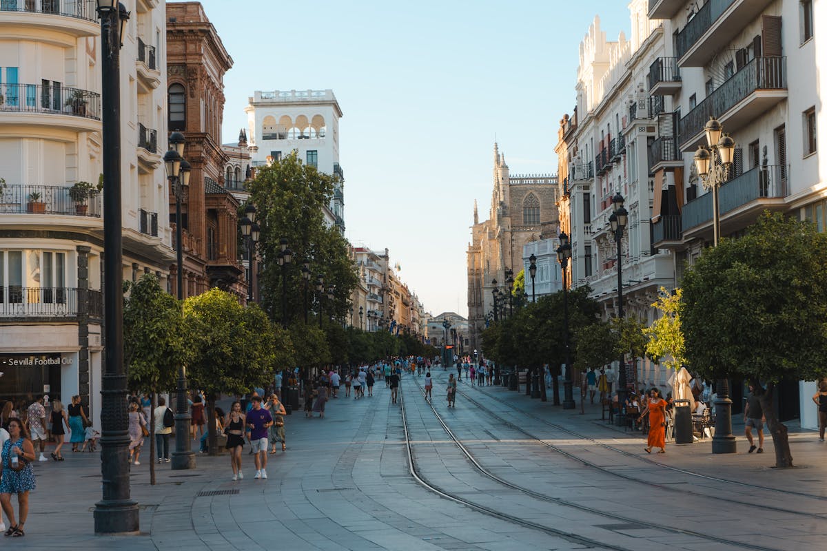 A sunny street in Seville Spain with people walking among historic buildings