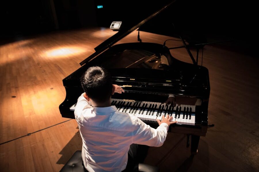 Pianist seen from behind playing a black grand piano
