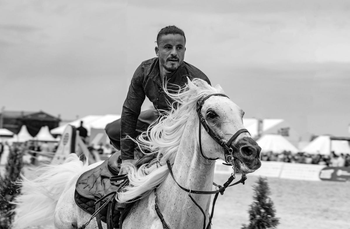 Man riding white horse during outdoor equestrian event