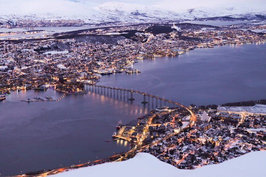 Aerial twilight view of Tromso cityscape and snowy landscapes