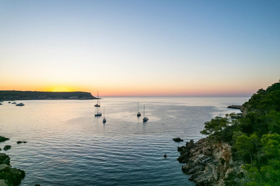 Sailing boats anchored in a bay during golden sunset in Sant Joan de Labritja Ibiza Spain