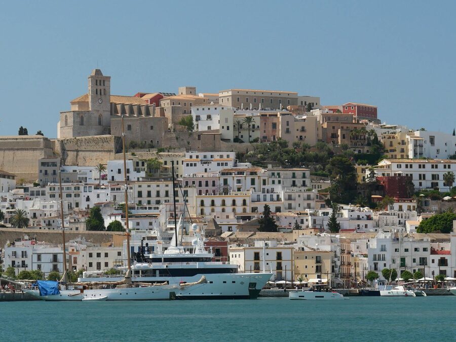 View of Ibiza historic Dalt Vila fortress with yachts anchored in harbor under blue sky