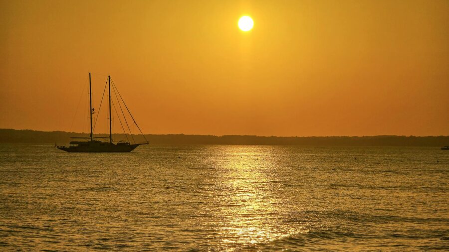 Sailing boat on calm waters during golden sunset in Ibiza Spain