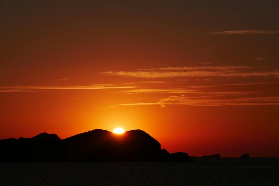 Orange sunset behind Ibiza island silhouette over the Mediterranean Sea