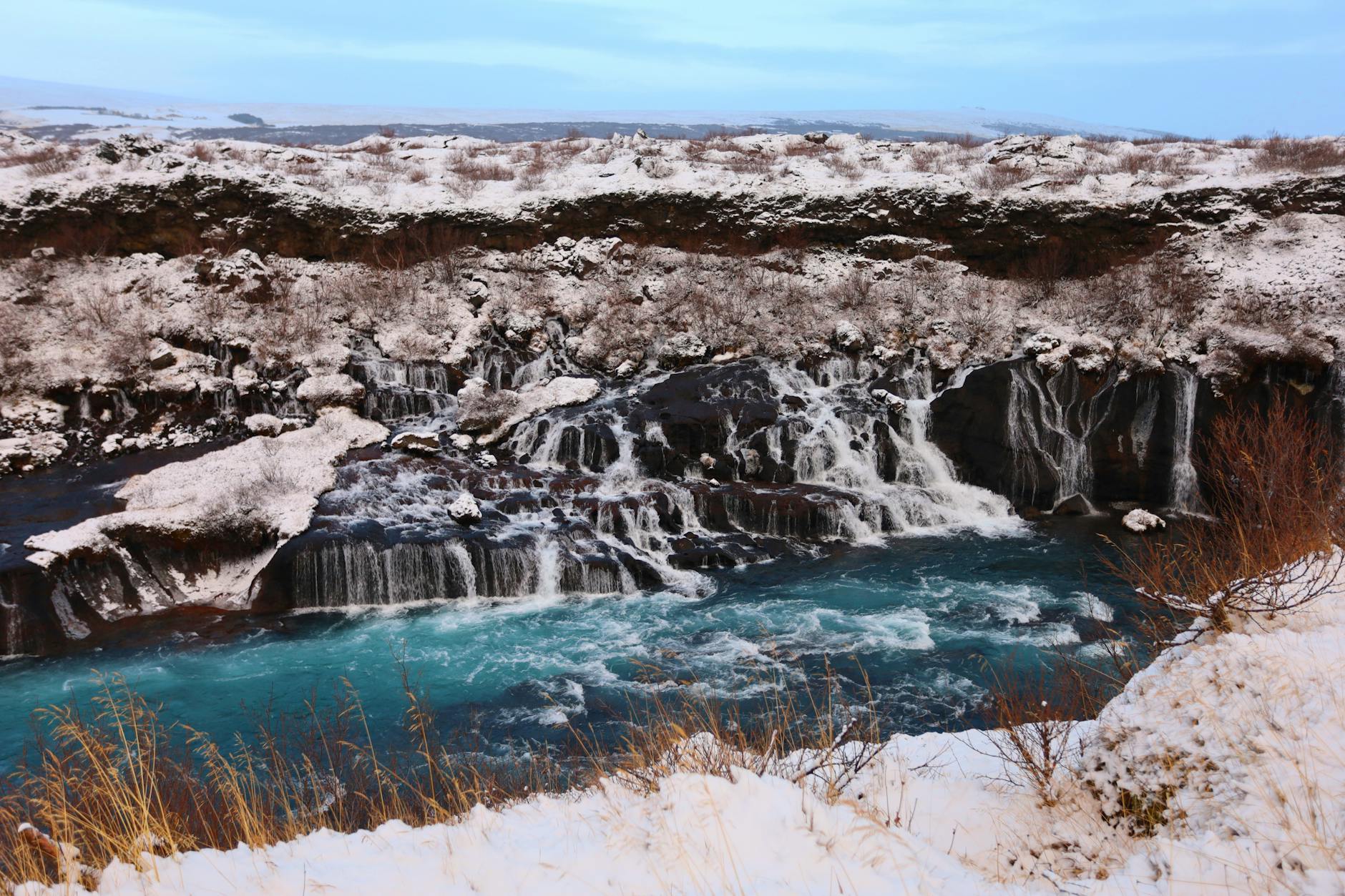 Icelandic waterfall in winter with ice formations and flowing water