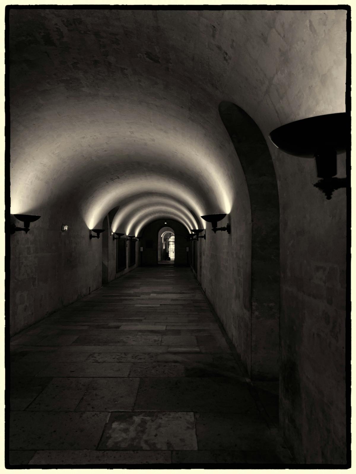 A dramatically lit stone hallway in an underground passage