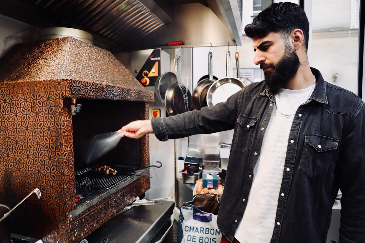 Professional chef grilling meat skewers in a traditional Paris kitchen