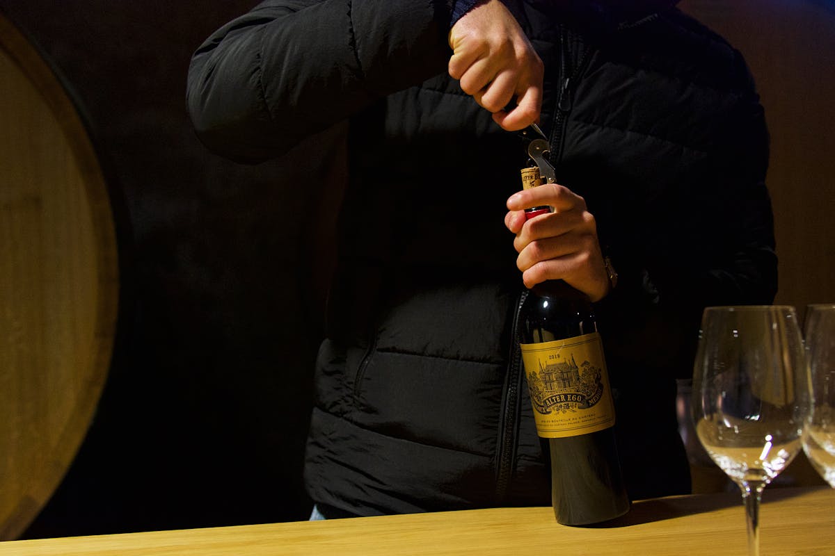 Person uncorking wine bottle during wine tasting in Margaux Bordeaux
