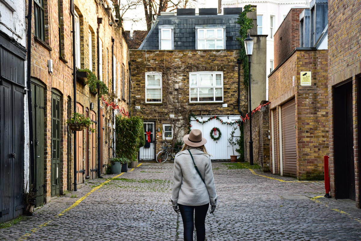 A lone figure walking through a narrow cobblestone alley in London