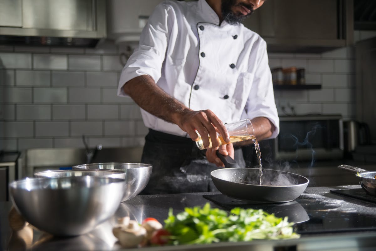 Professional chef preparing food in a modern kitchen with a frying pan