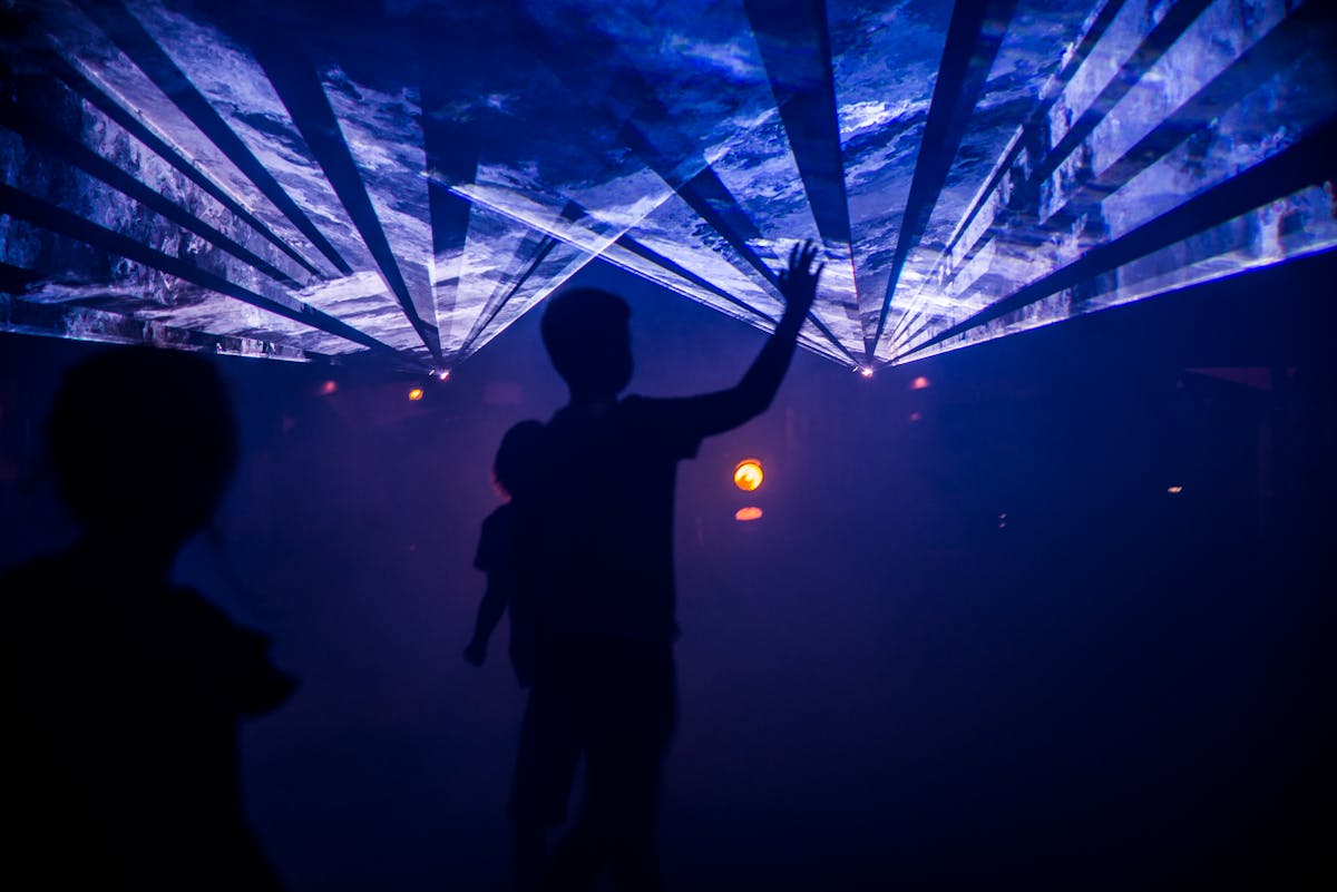 Silhouette of people interacting with an artistic indoor light display