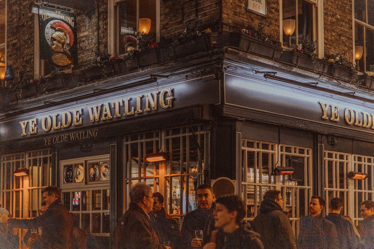Ye Olde Watling pub in London lit up at night with warm interior glow