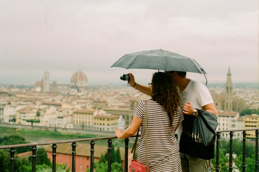 Couple under umbrella photographing Florence skyline from elevated viewpoint