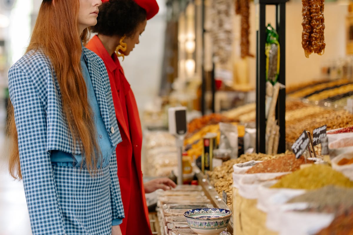Women exploring a colorful spice market with various ingredients on display