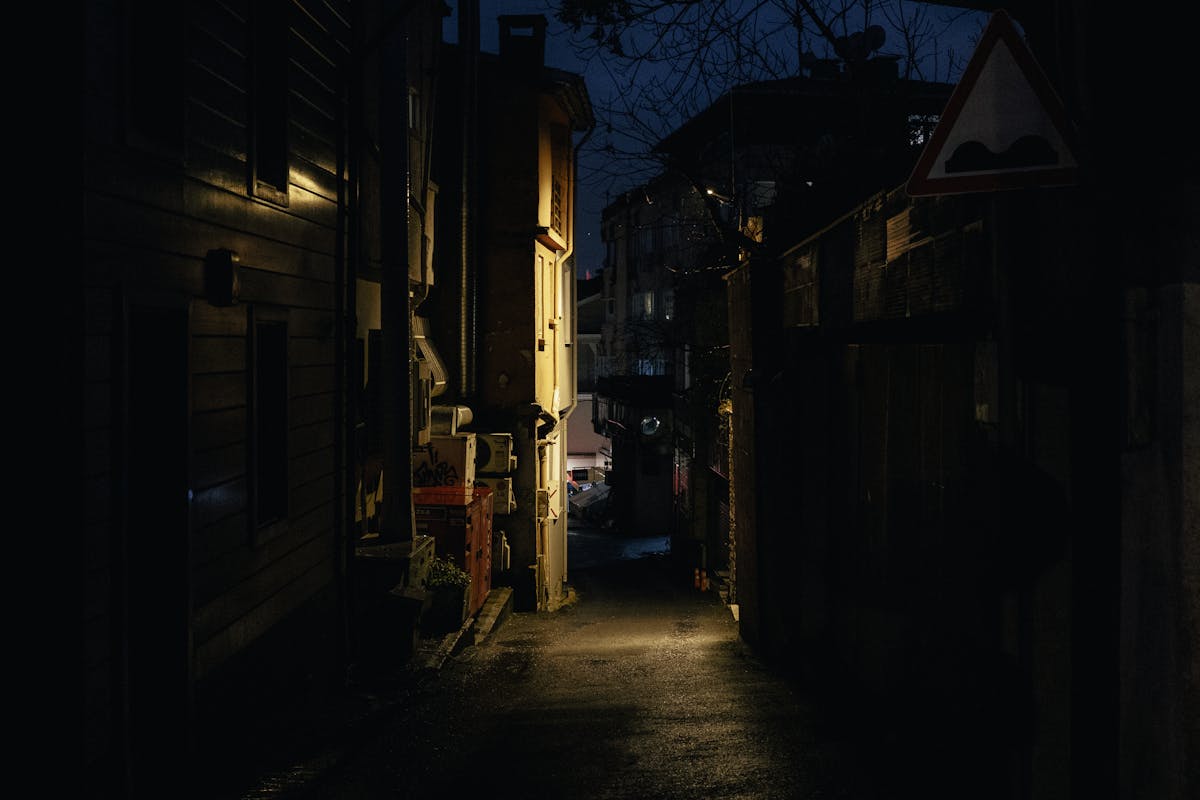 A dimly lit narrow alleyway at night with minimal lighting