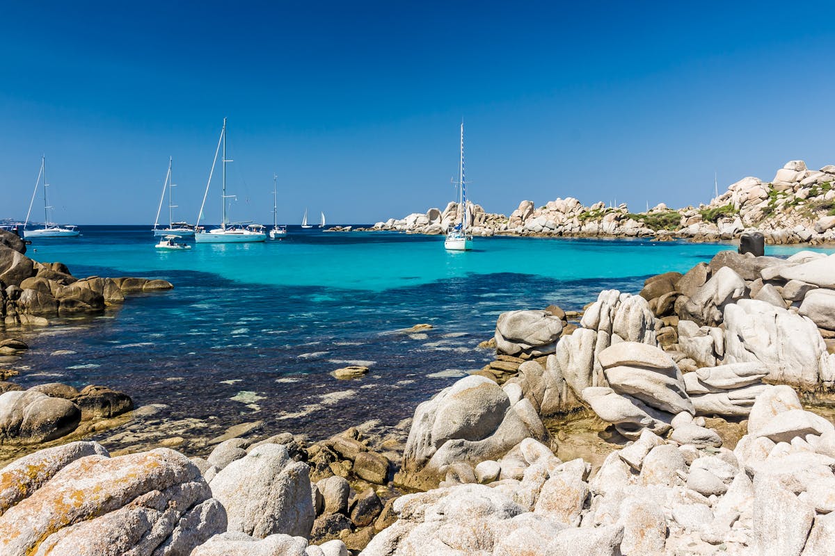 Crystal clear turquoise water on a Corsican beach with rocky coastline
